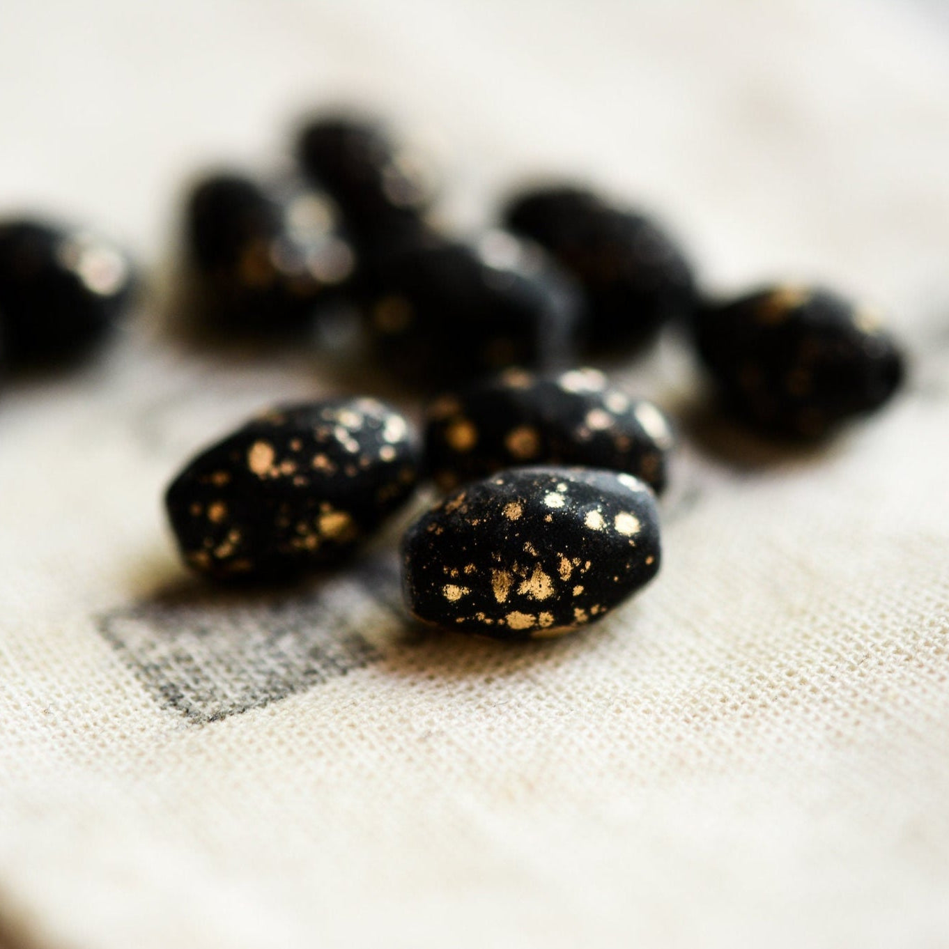 Black stones with gold speckles on a textured white surface