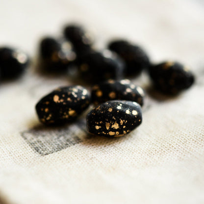 Black stones with gold speckles on a textured white surface